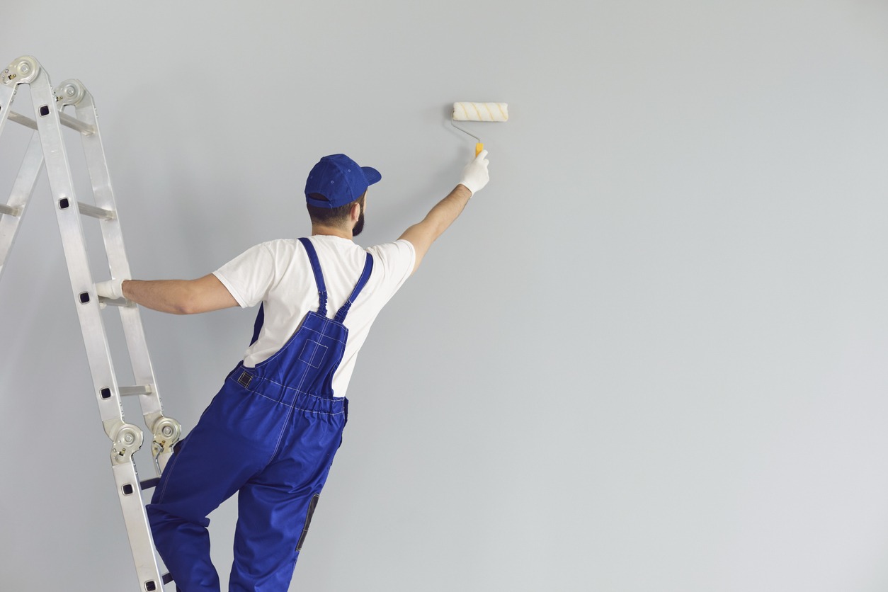 Painter painting grey wall. Professional builder makes repairs