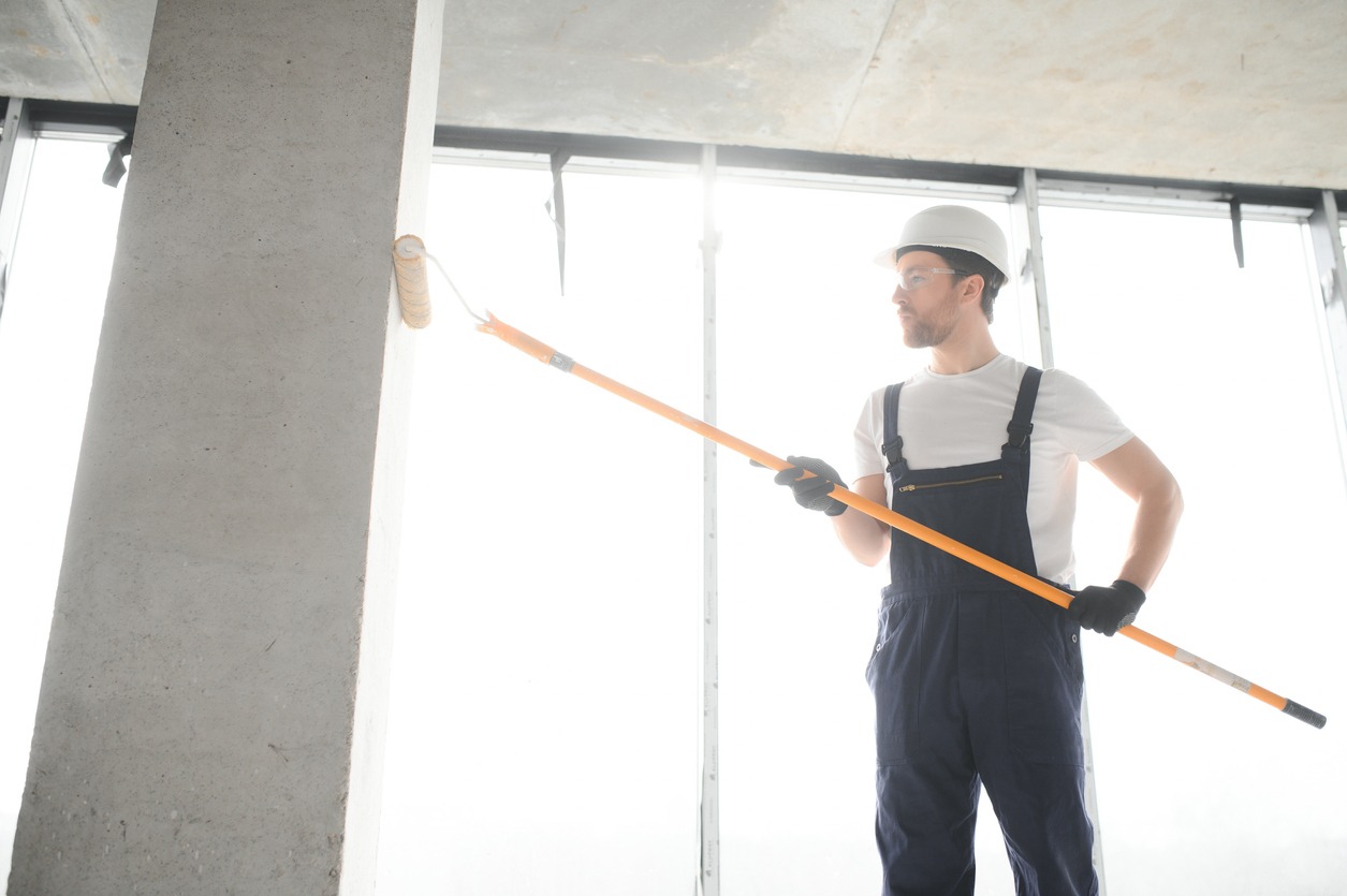 Painter man painting the wall, with paint roller.