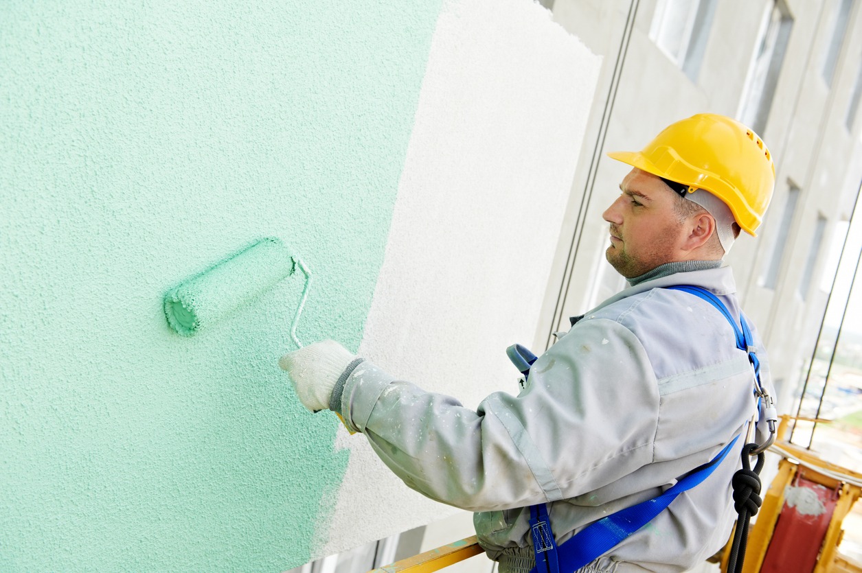 Construction worker painting building facade with green tone