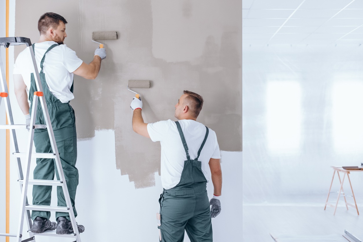 Man on ladder painting wall