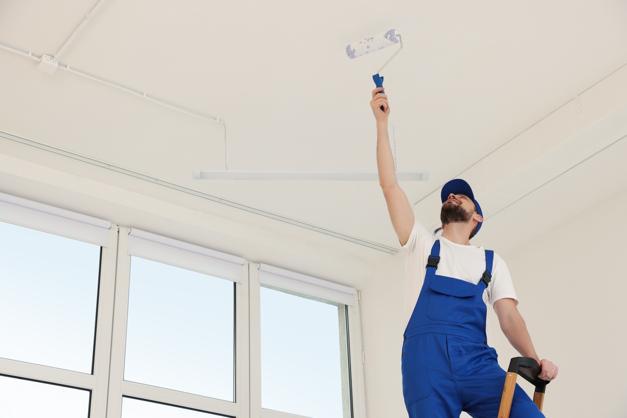 Worker in uniform painting ceiling