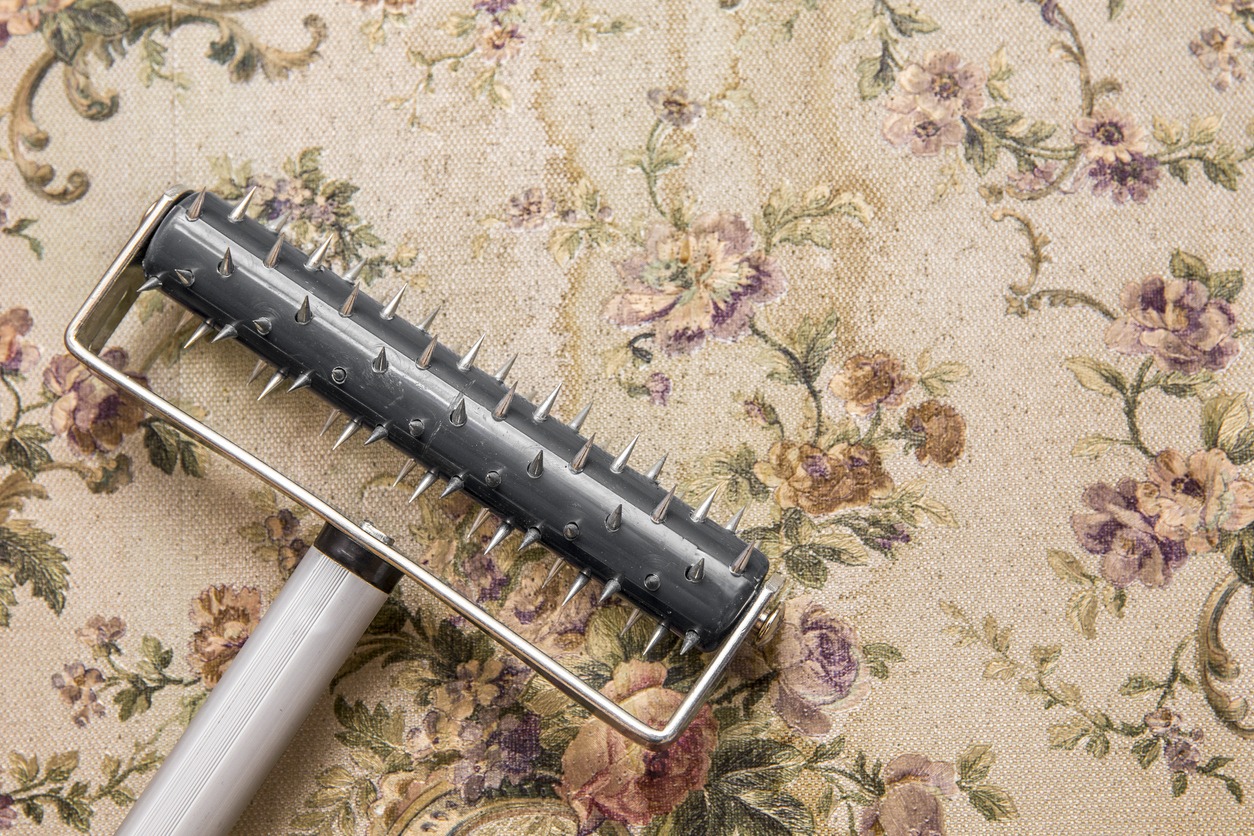 Removing old water damaged retro style wallpaper with rolling spike scoring tool