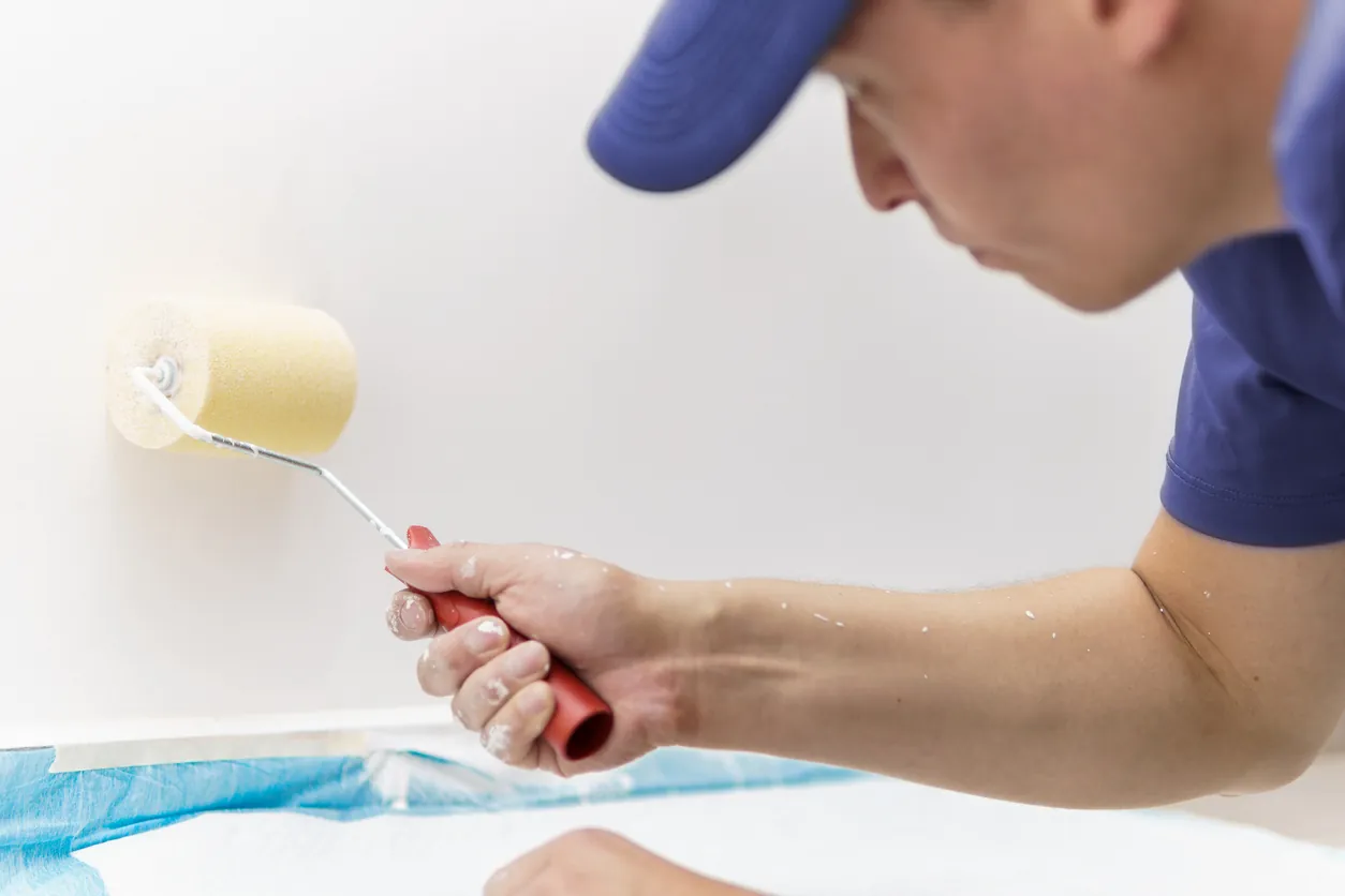 a man crouching on the floor with a roller painting