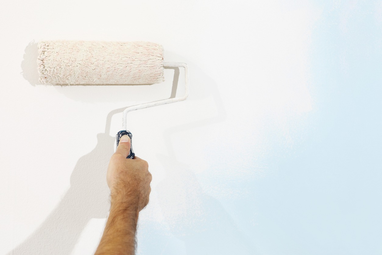 hand painter man at work with paint roller, wall painting