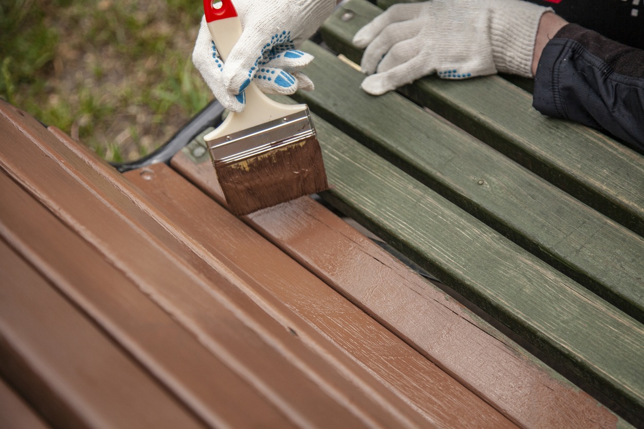 The bench in the park is painted in brown.