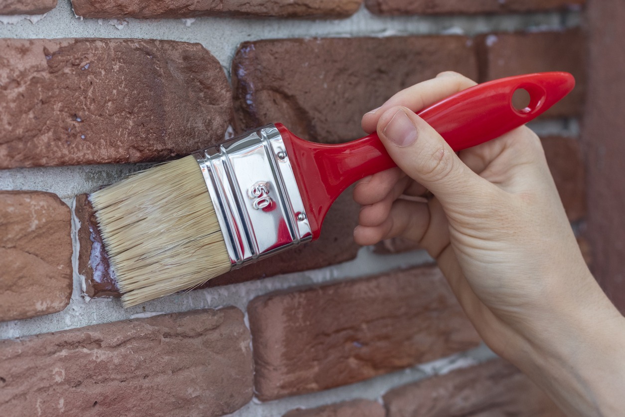 Female hand applying varnish to decorative plaster tile.