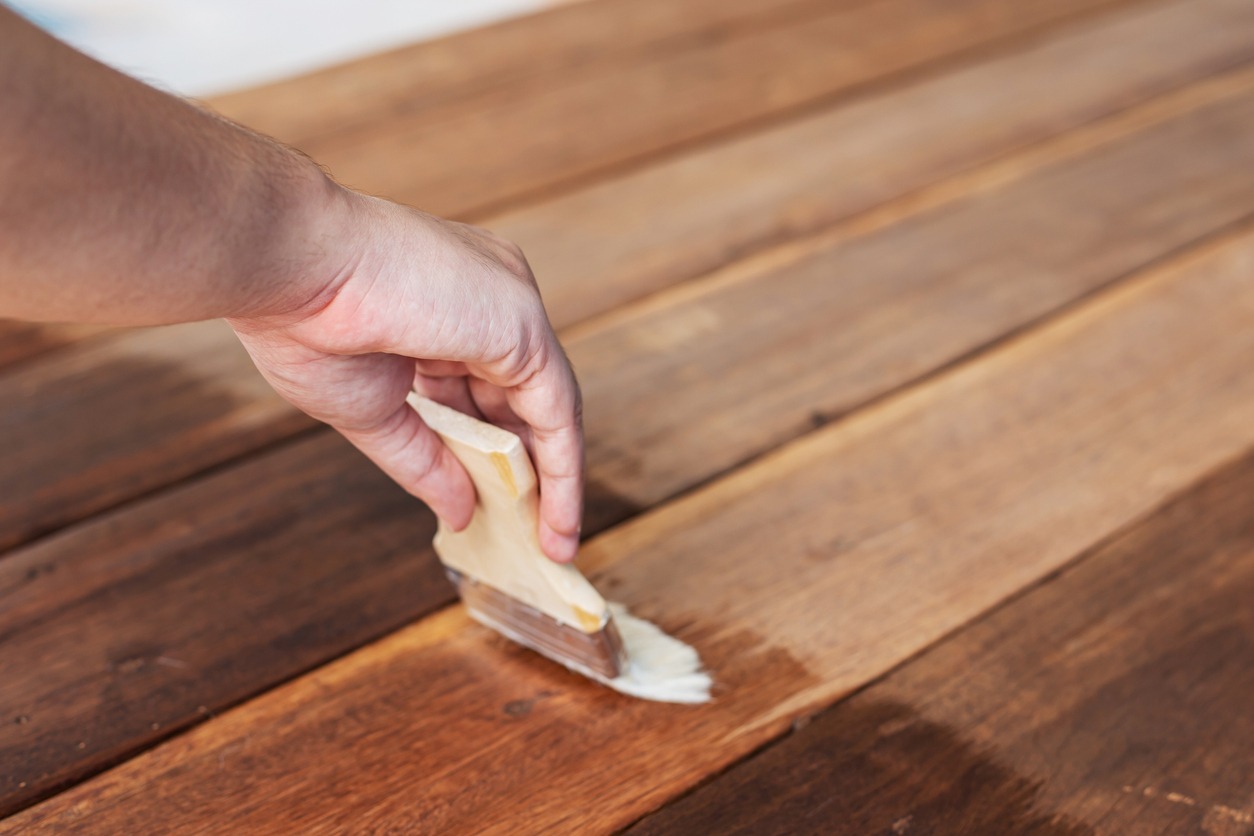 A man hands holding paintbrush and paints gross varnish