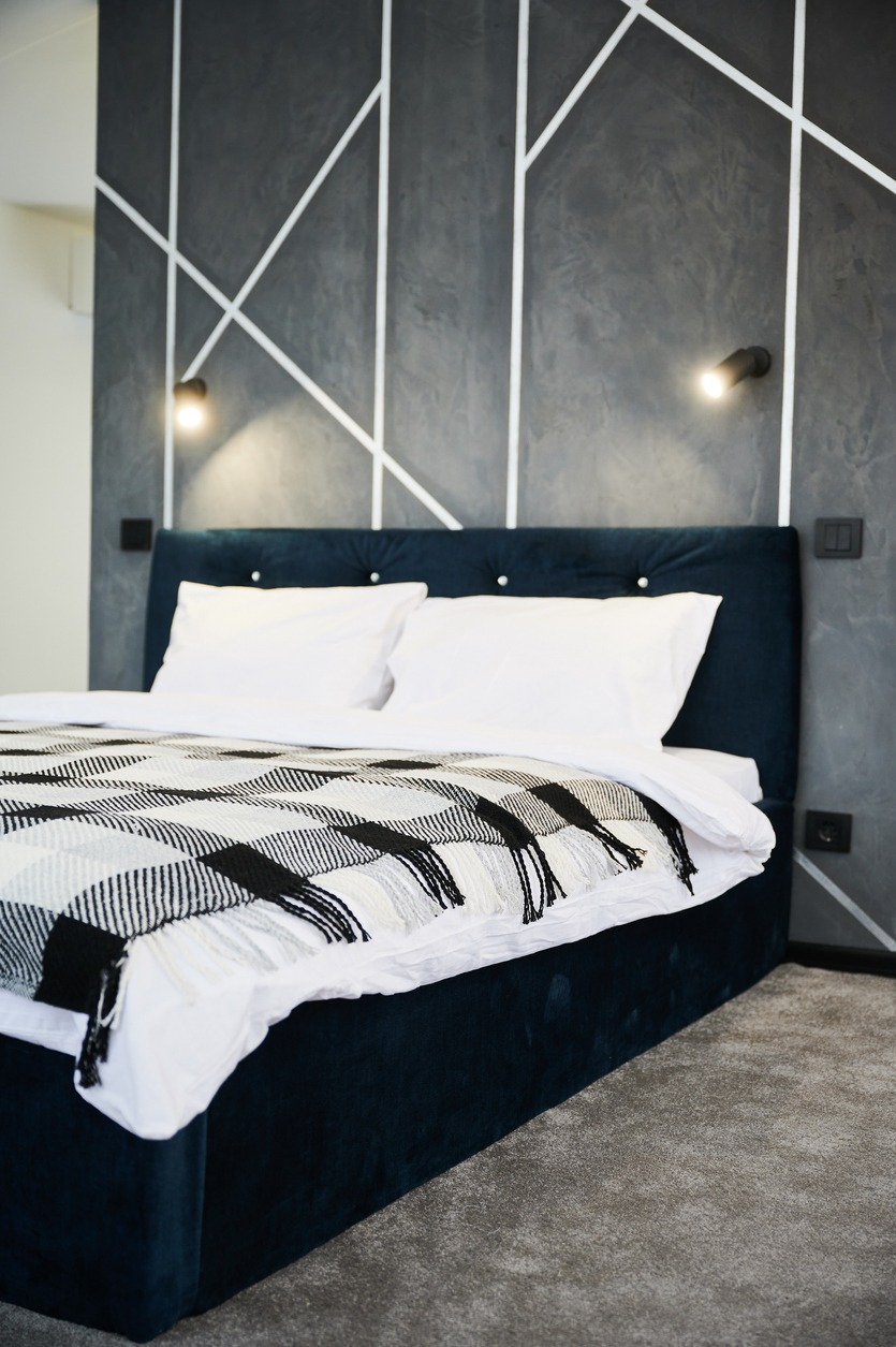 Bedroom interior with black bed and soft light hanging against gray wall.