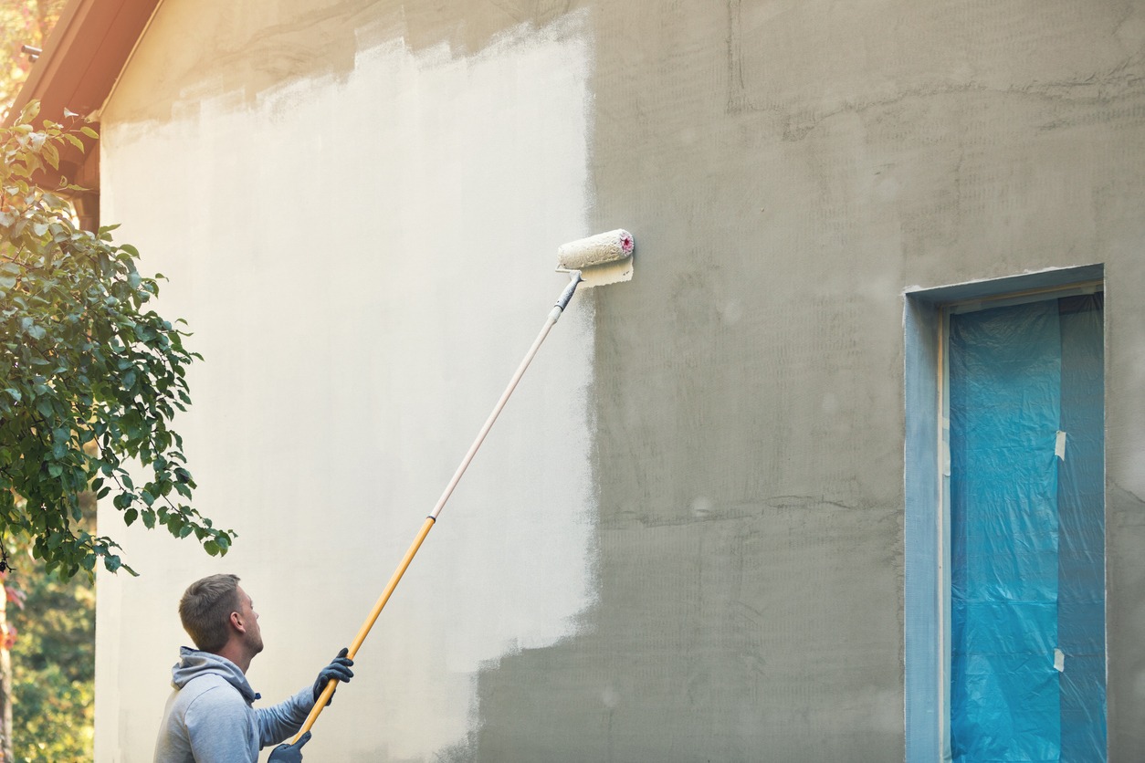 house painter painting building exterior with roller