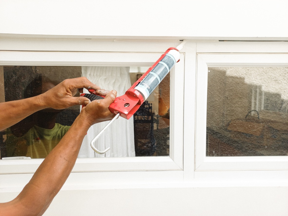 Construction worker using silicone sealant caulk the outside window frame.