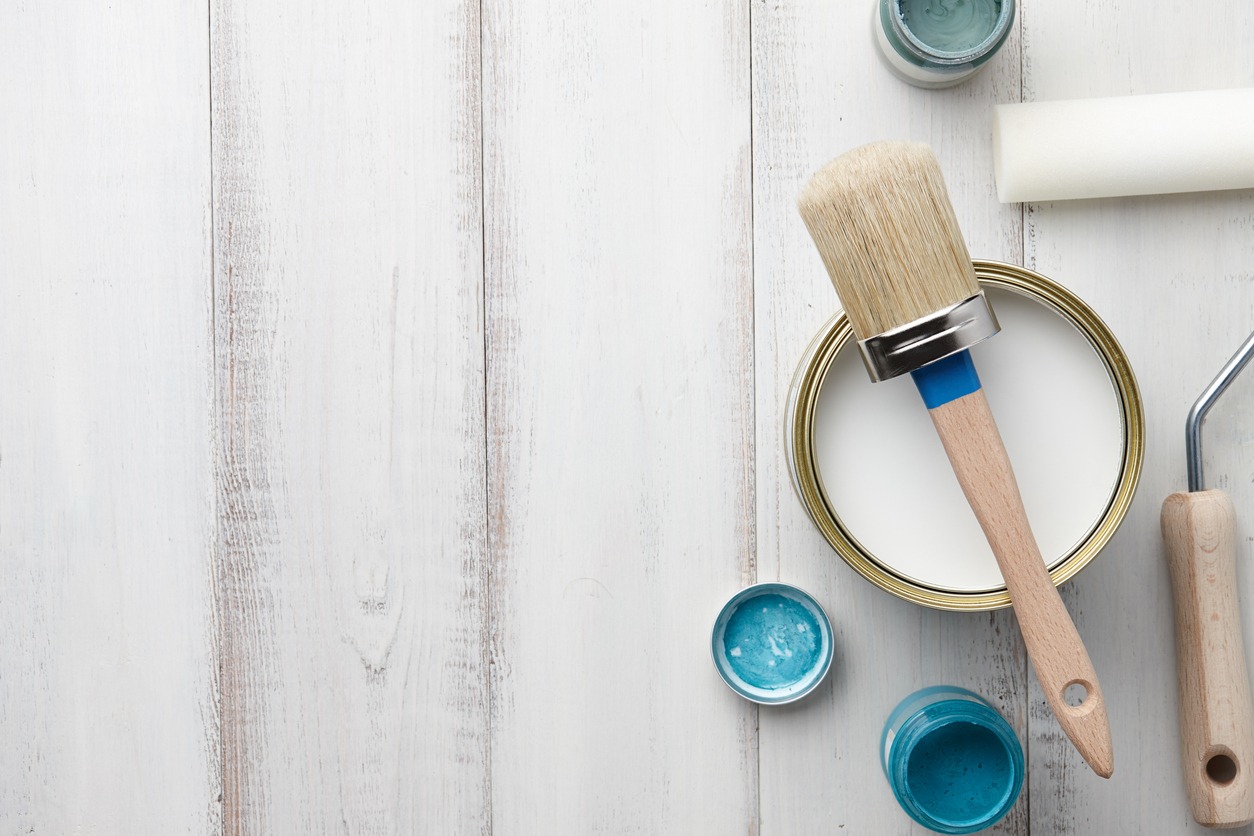 Paint, brush and other painting supplies on white wooden table