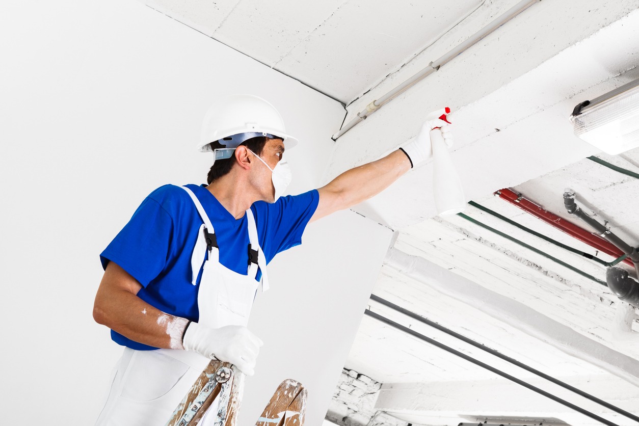 Worker spraying ceiling with spray bottle