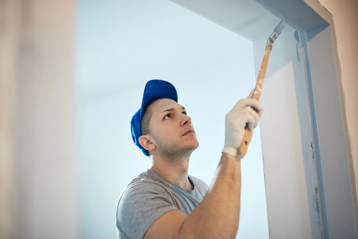 Young adult man painting on a DIY budget renovation of his new home apartment.